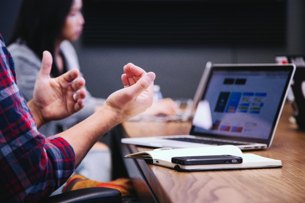 Online learning and collaboration depicted by hands gesturing toward a computer screen